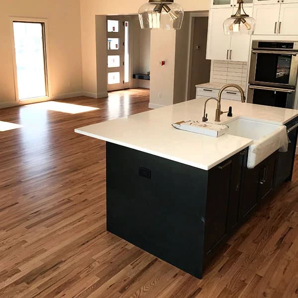 new hardwood floors in updated kitchen with black cupboards and white countertops