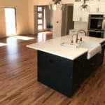new hardwood floors in updated kitchen with black cupboards and white countertops