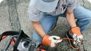 Worker kneeling down looking at the screen of a residential sewer camera
