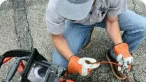 Worker kneeling down looking at the screen of a residential sewer camera