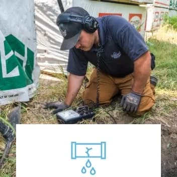 man on grass outside using a device to diagnose plumbing problem