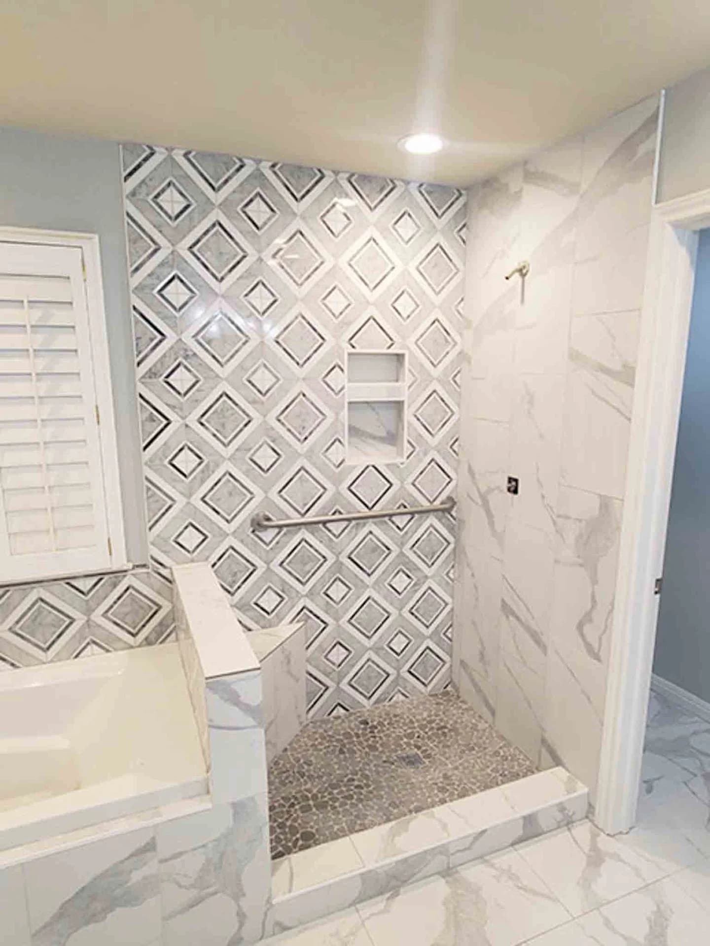 A white tile bathroom with a stand up shower, done by Footprints Floors.
