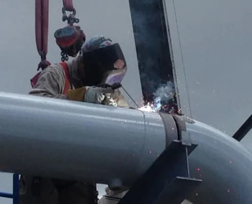 Close Up Of Person Wearing Safety Mask Welding On Metal Pipe