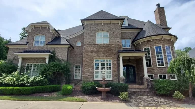 A freshly painted house in Cary, NC with stone and cream trim completed by A Touch of Color Painting & General Contracting.