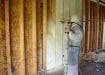 masked worker applying spray foam on wall