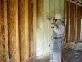 masked worker applying spray foam on wall