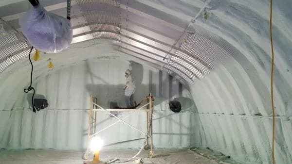 worker applying spray foam in pole barn