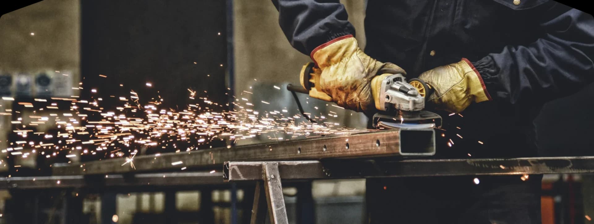 Worker grinding metal with sparks flying.