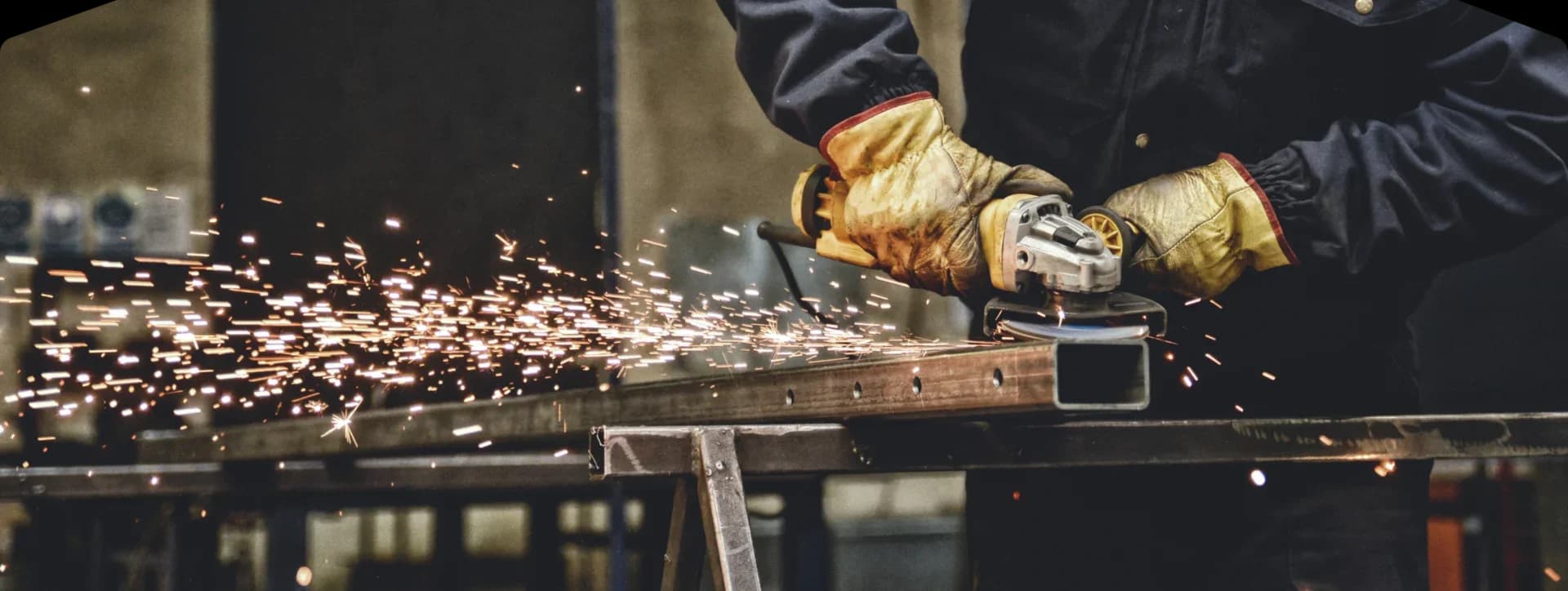 Worker grinding metal with sparks flying.