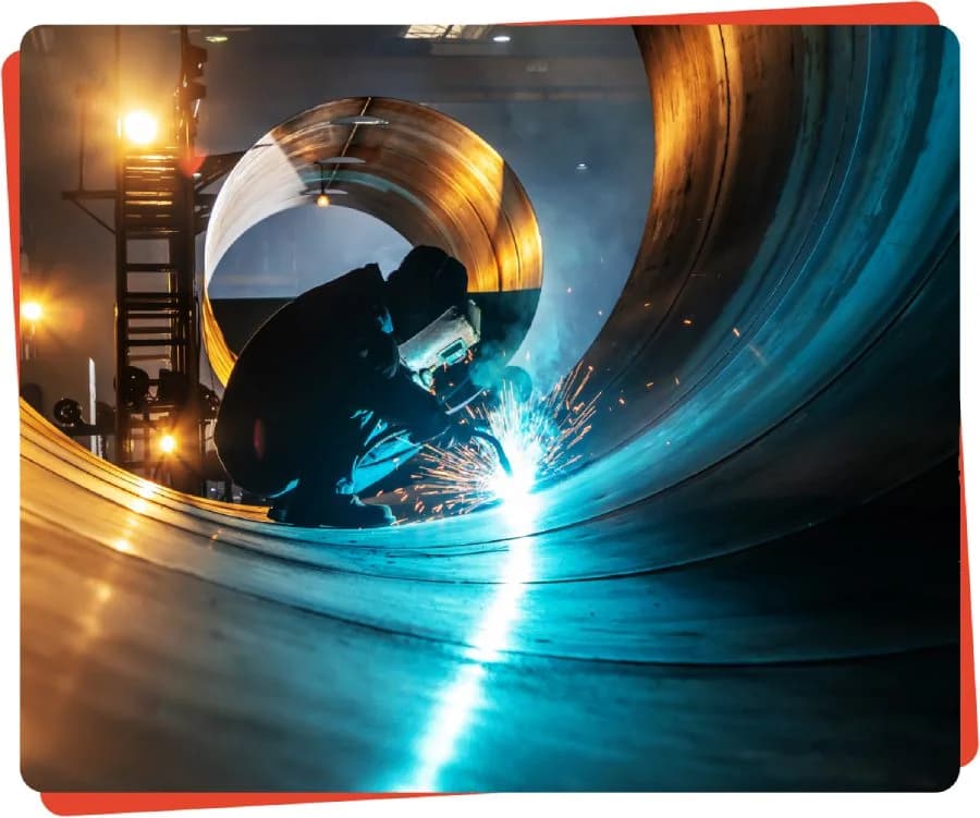 Welder working on large metal pipe.