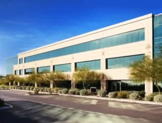 Exterior of a large commercial building and parking lot on a sunny day.