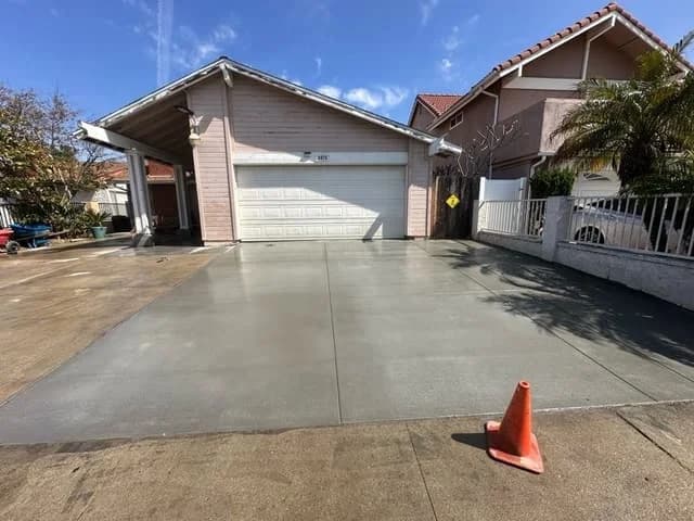Finished concrete driveway at a pink stucco home in San Diego