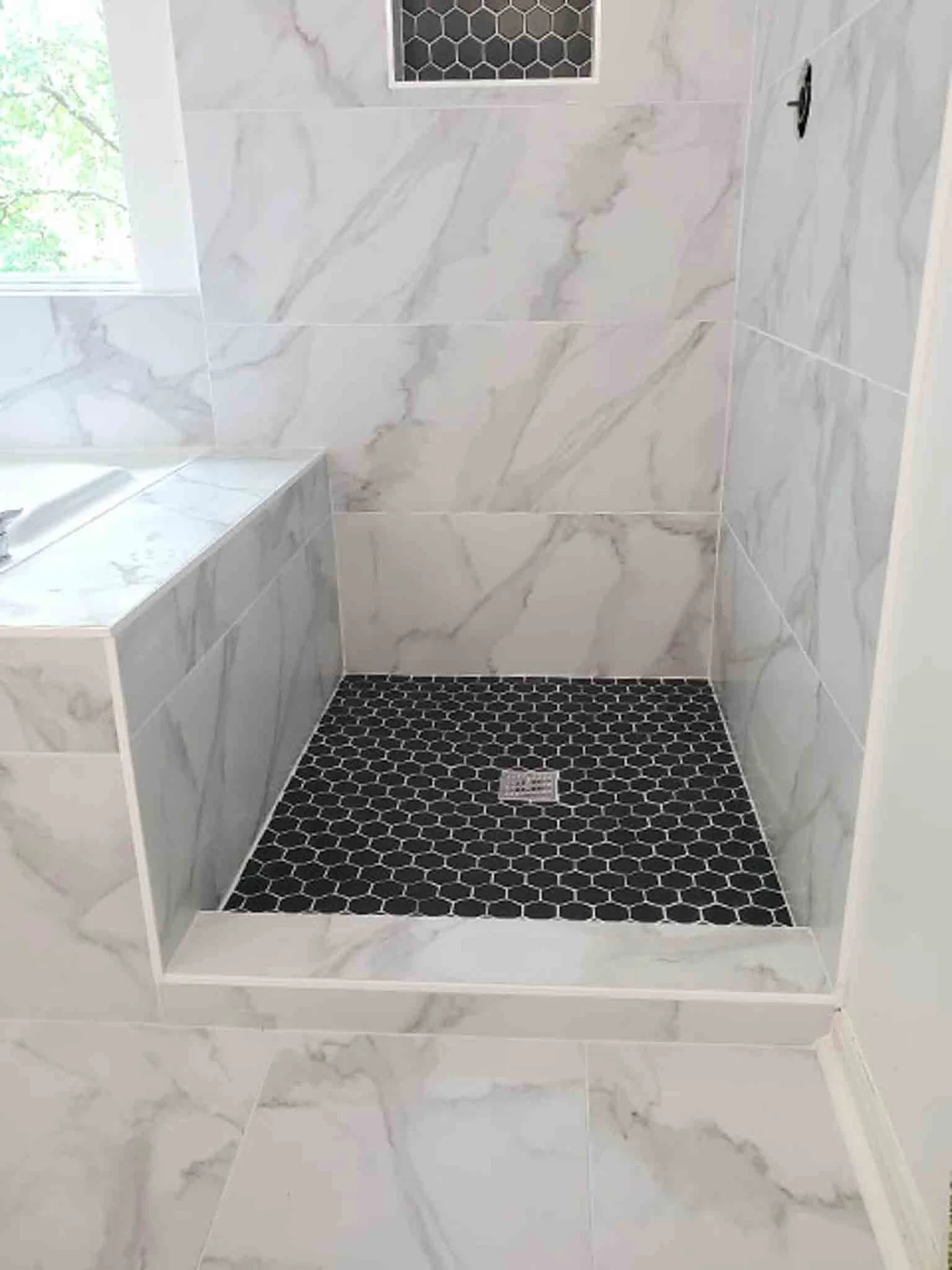 A white stand up shower with black tiling, installed Footprints Floors.