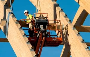 construction worker on lift working on wooden beams