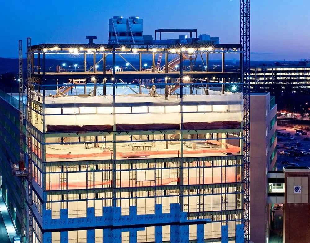 rooftop view of tall building under construction with large metal beams and bright lights