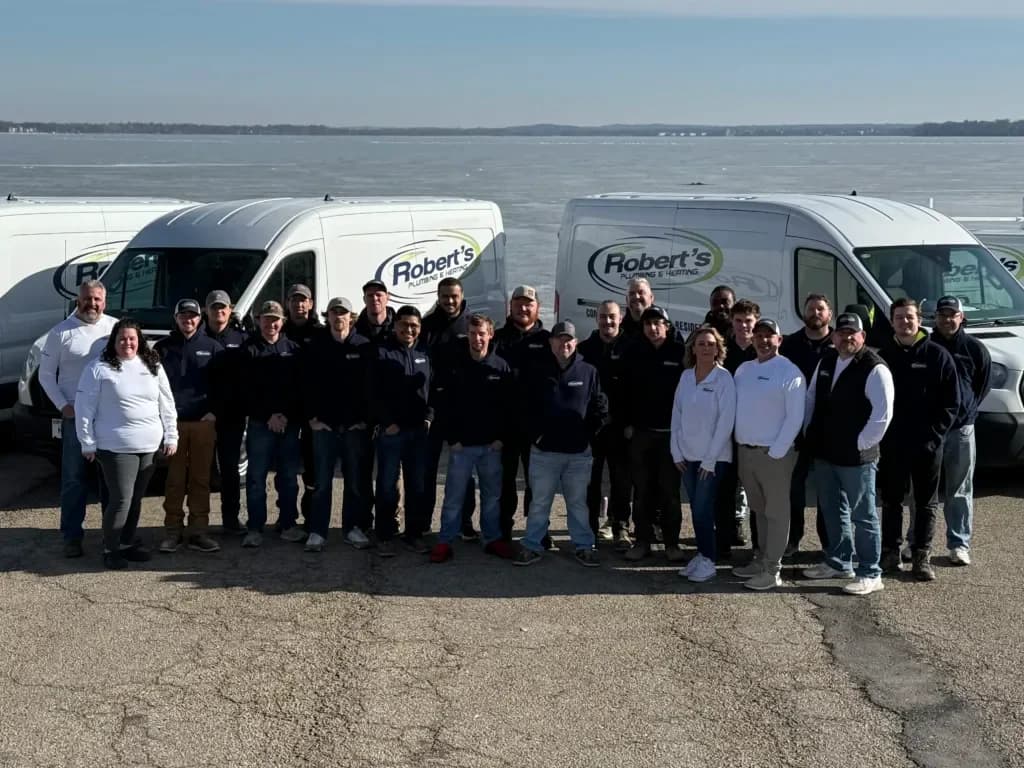 Robert's Plumbing team standing in front of work vans parked next to a lake in Madison, Wi. Team is posing together