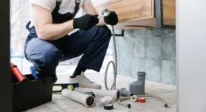 Plumber man fix repair service wraps fluoroplastic sealing material tape around faucet hose.