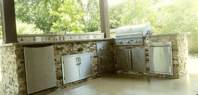 Outdoor kitchen featuring custom stone cabinetry, stainless steel appliances, and a grill, designed for functionality and style in home remodeling.