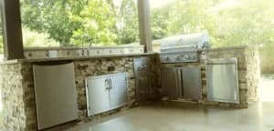 Outdoor kitchen featuring custom stone cabinetry, stainless steel appliances, and a grill, designed for functionality and style in home remodeling.