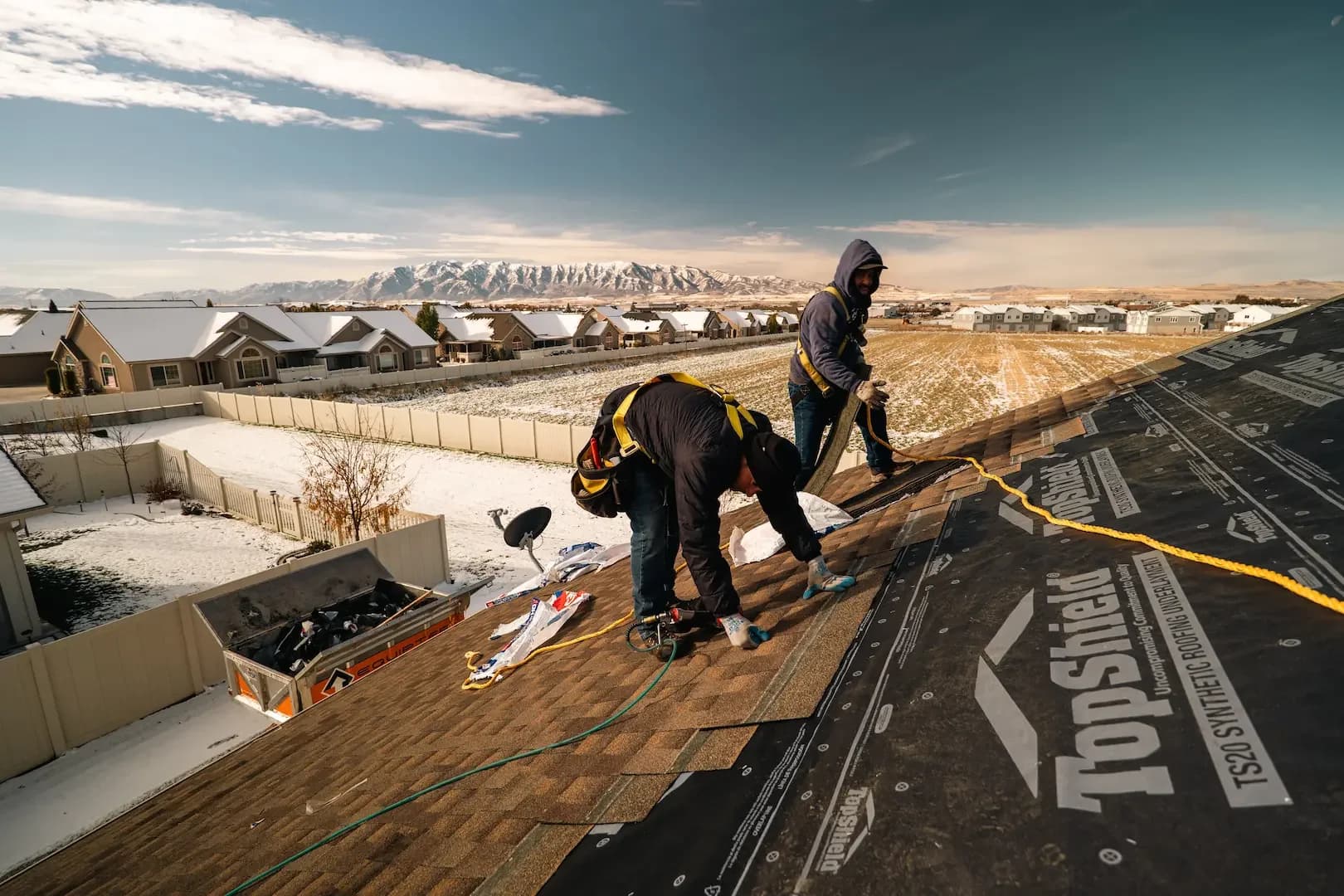 Homer Roofing crew installing new roof in Northern Utah winter with Wasatch Mountains in background