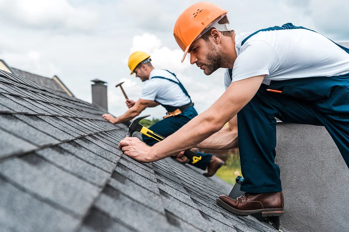 selective focus of handsome handyman repairing roof with coworker