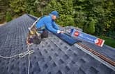 Person working on a roof with a GAF product visible