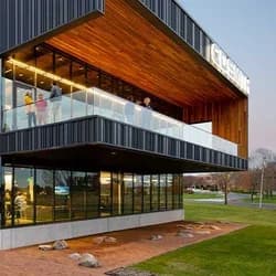 Exterior view of C.D. Smith Construction's corporate headquarters in Fond du Lac, WI, illuminated by lights at dusk. The building showcases modern architecture and integrated building solutions