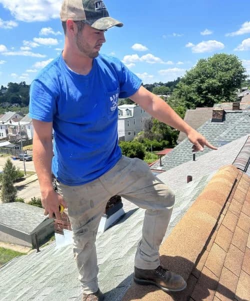 Roofing contractor inspecting shingles on a residential roof in Pittsburgh, showcasing hands-on expertise in roofing services.