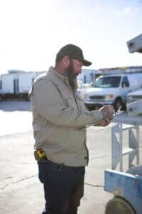 Commercial electrician inspecting an electrical installation project and taking notes on a clipboard