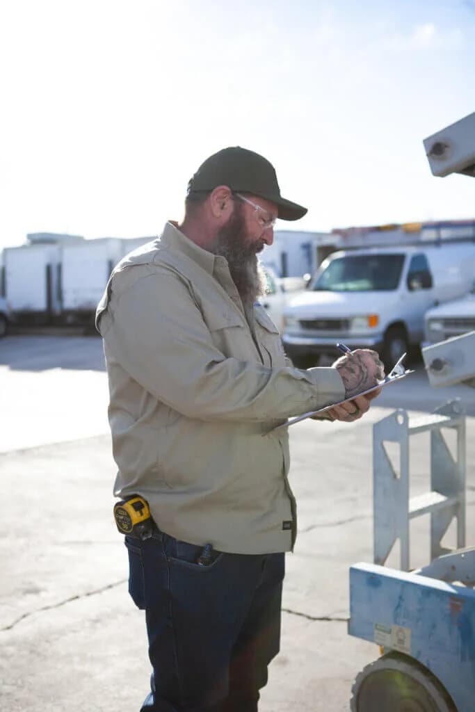 Commercial electrician inspecting an electrical installation project and taking notes on a clipboard