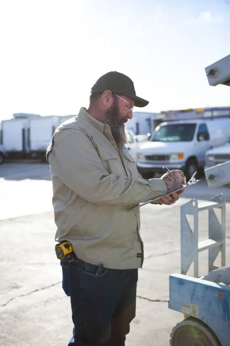 Commercial electrician inspecting an electrical installation project and taking notes on a clipboard