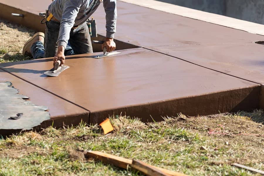 worker smoothing concrete before stamping it