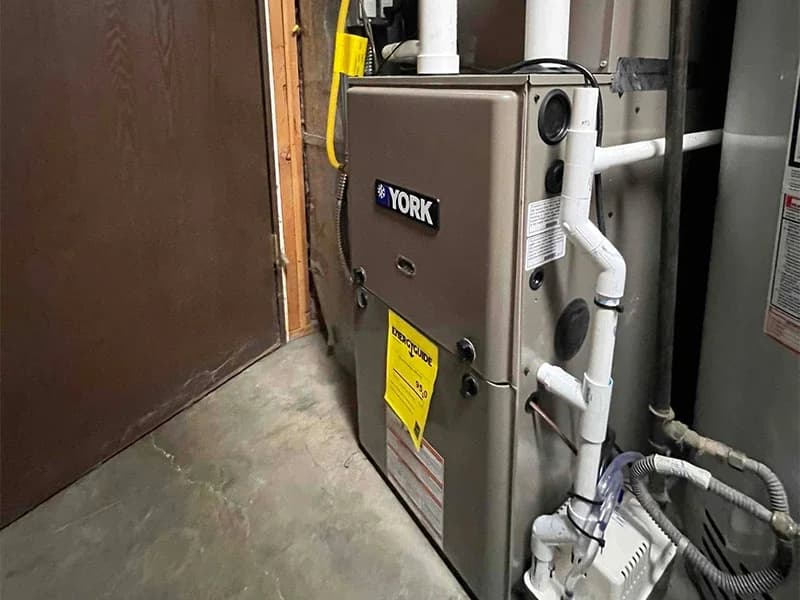 A side shot of a quality furnace install that showcases the complex drain piping and Bills Heating and AC's professionalism.