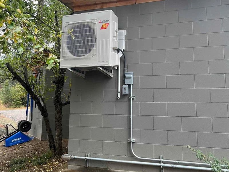 A Mitsubishi Ductless condenser from their hyper-heat line, mounted on an exterior wall of a building.