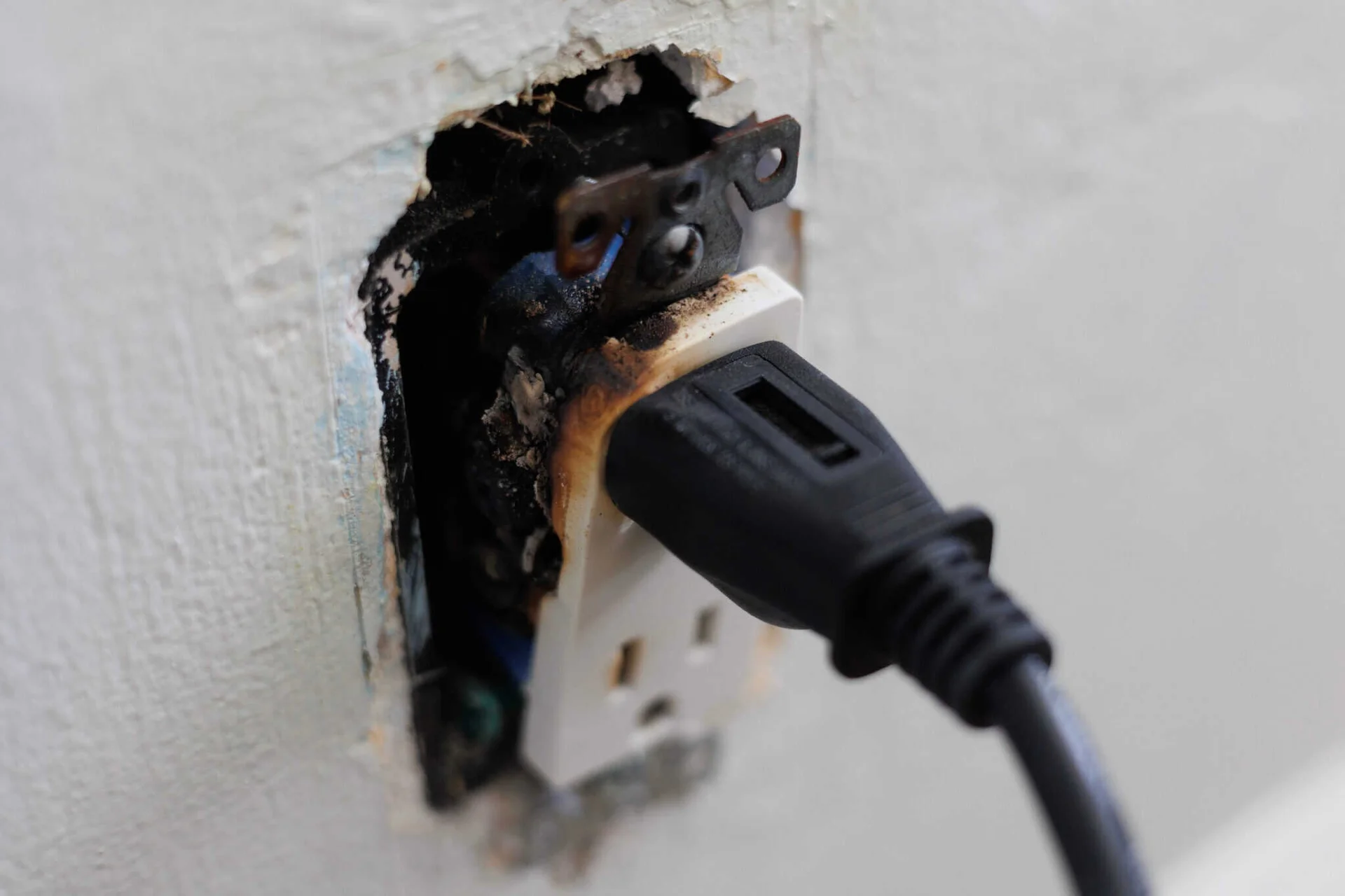 Close-up of a damaged electrical outlet and plug during troubleshooting.
