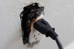 Close-up of a damaged electrical outlet and plug during troubleshooting.