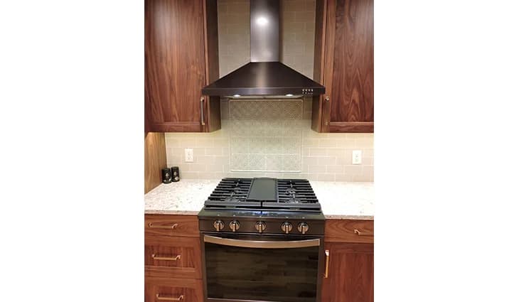 Remodeled kitchen with new wood cabinets and a brand new stove with a fan above it
