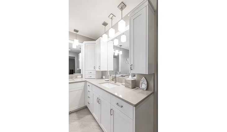 Remodeled white bathroom cabinets with tan granite countertops and a wood floor