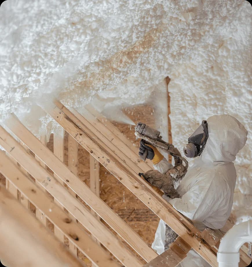 Worker applying spray foam insulation in attic.