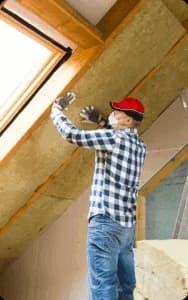 A contractor performing insulation installation in a client's attic.