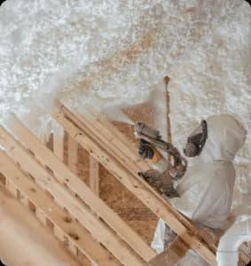 Worker applying spray foam insulation in attic.