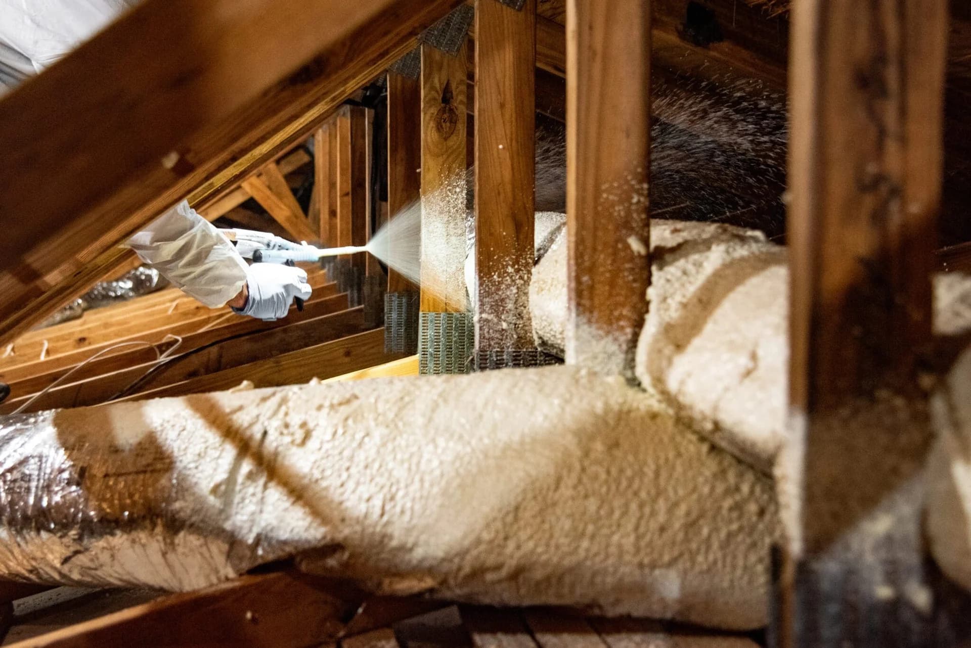 A professional applying protective spray foam insulation in an attic.