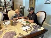 Roofers discussing roofing options with a senior homeowner.