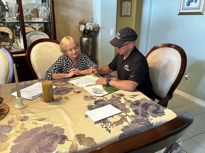 Roofers discussing roofing options with a senior homeowner.