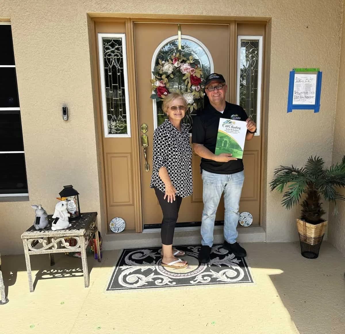 Homeowner and roofer standing at front door with inspection report.