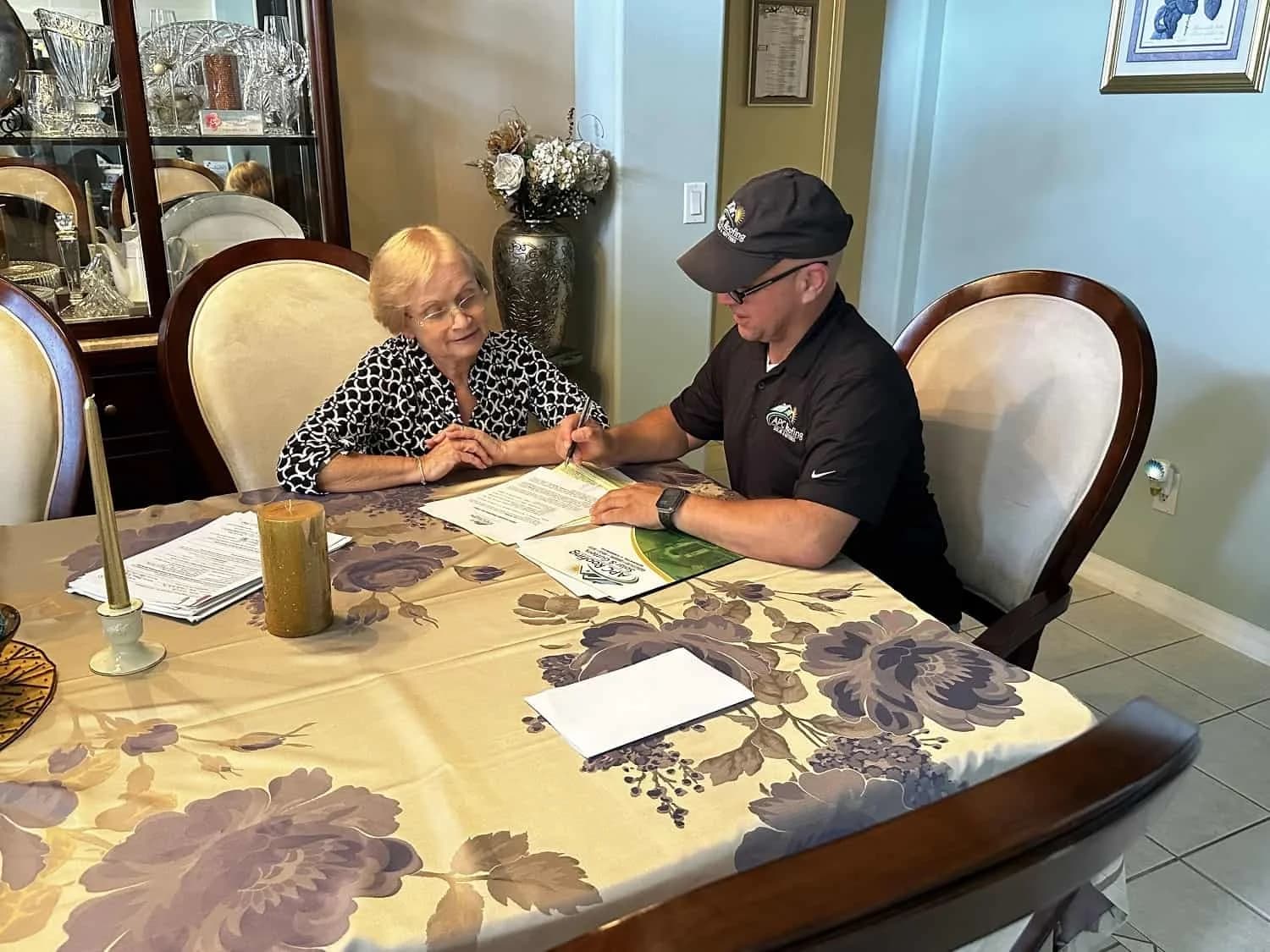 Roofers discussing roofing options with a senior homeowner.