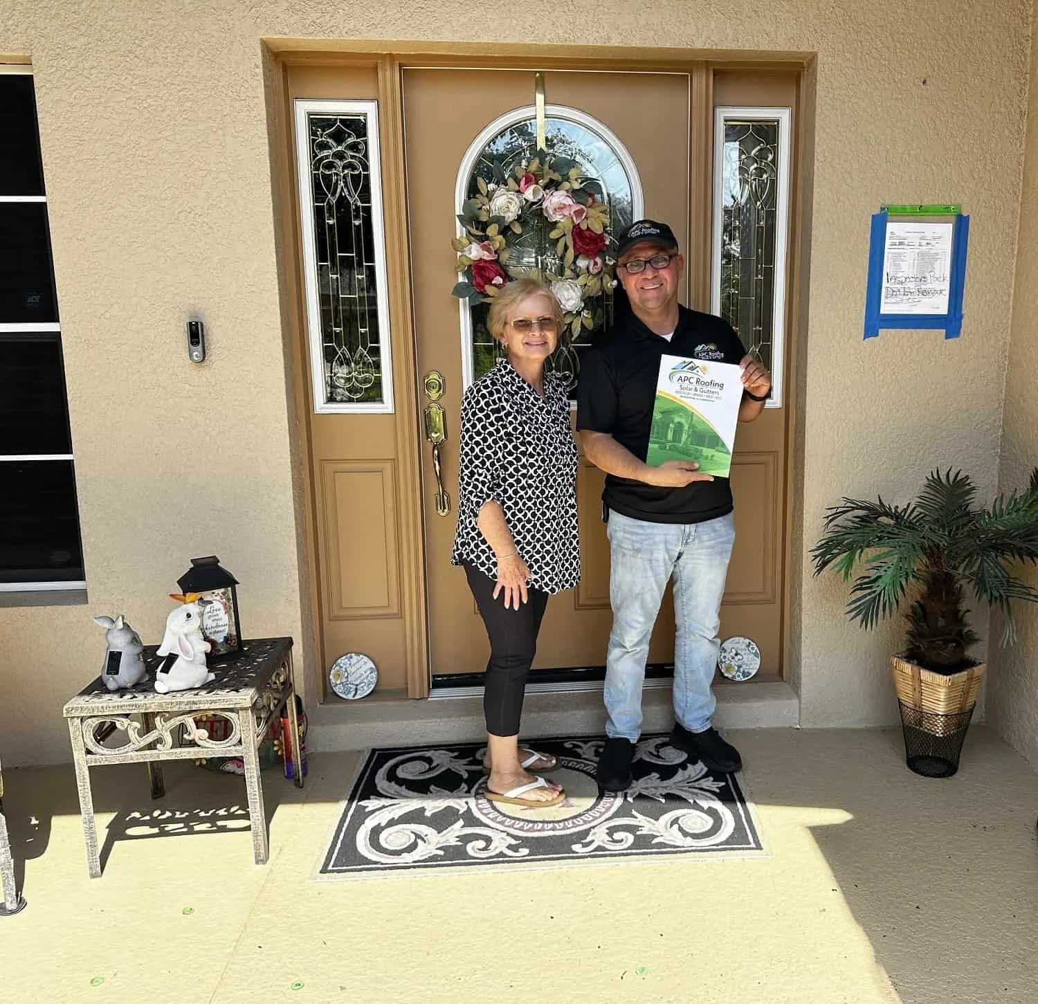 Homeowner and roofer standing at front door with inspection report.