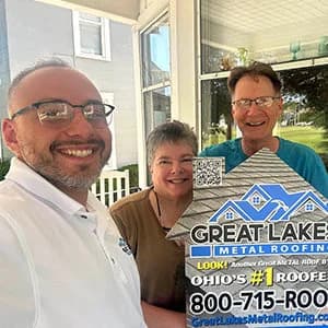 two clients and a sale representative for Great Lakes Home Remodeling holding a sign for Great Lakes Metal Roofing in front of a house