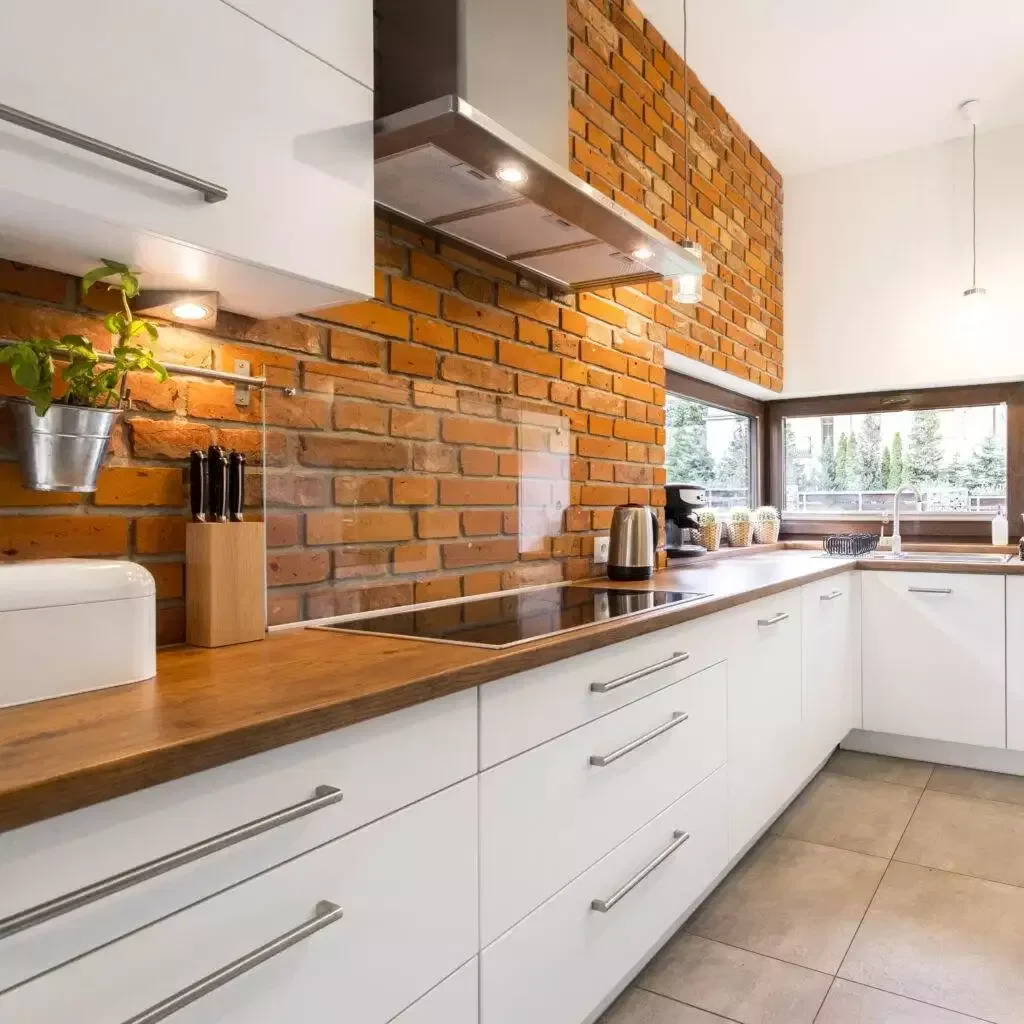 a kitchen with brick wall and white cabinets