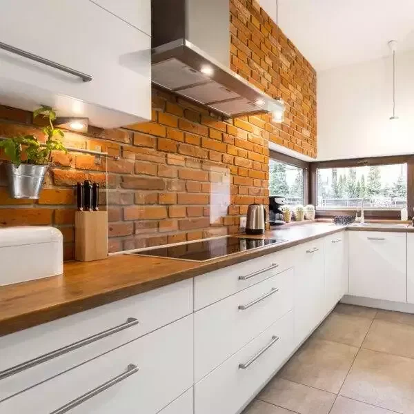 a kitchen with brick wall and white cabinets